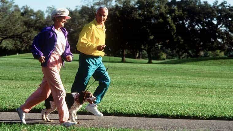Pareja de ancianos corriendo en el parque con perro