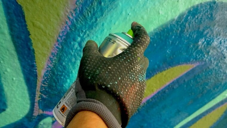 Primer plano de la pared de pintura de aerosol de mano humana.